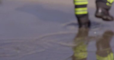 Bir itfaiyecinin kararlı adımlarını yakına çekerek itfaiye aracına doğru yürürken sarsılmaz bir adanmışlıkla acil bir duruma müdahale etmeye hazır olduğunu gösterir.. 