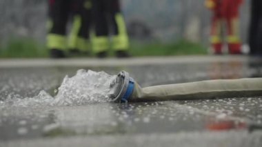 Yakın çekim, güçlü bir su akışına sahip bir yangın hortumunu yakalar, itfaiye aracının hassasiyetini ve gücünü vurgular.. 