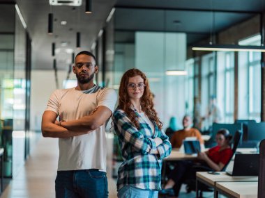 Afro-Amerikalı iş adamı ve iş kadını meslektaşı kollarını kavuşturarak önde duruyorlar. Kendilerine güveniyorlar ve liderlik ediyorlar. Çeşitli ekipleri ise özenle arkalarında çalışıyor.