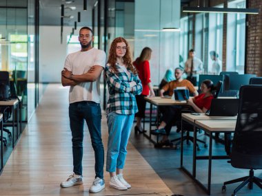 Afro-Amerikalı iş adamı ve iş kadını meslektaşı kollarını kavuşturarak önde duruyorlar. Kendilerine güveniyorlar ve liderlik ediyorlar. Çeşitli ekipleri ise özenle arkalarında çalışıyor.