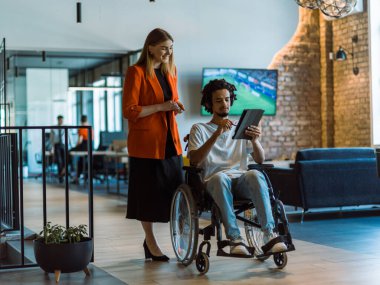 Tekerlekli sandalyedeki Afro-Amerikalı işadamı, iş arkadaşı ile tablet kullanarak uyumlu teknolojinin kusursuz bütünleşmesini ve