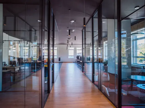 In a setting of modern, glass-walled business startup offices, the open, airy workspace reflects a contemporary and innovative ambiance, promising a dynamic environment for entrepreneurial growth.