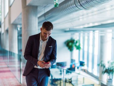 Gösterişli bir şirket ortamında, genç ve karizmatik yönetmen koridorda güven içinde yürüyor, dinamik liderliğini ve şirket içindeki başarısının devamını simgeliyor.