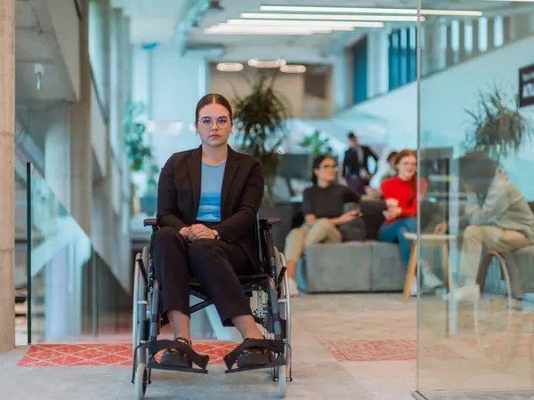 In a modern office, a young businesswoman in a wheelchair is surrounded by her supportive colleagues, embodying the spirit of inclusivity and diversity in the workplace.