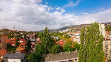 Uçan İHA 'lar şehir binalarının üzerinde, ağaçların tepesinde ve kalabalık caddelerde trafik varken çekim yaptı. Sinematik kurgu çekimi. 