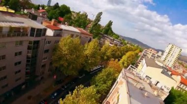 Uçan İHA 'lar şehir binalarının üzerinde, ağaçların tepesinde ve kalabalık caddelerde trafik varken çekim yaptı. Sinematik kurgu çekimi. 