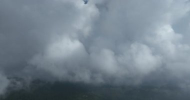 Bulutların ve dağların bulutlu bir yaz gününde yeşil ormanlı havadan görüntüsü.