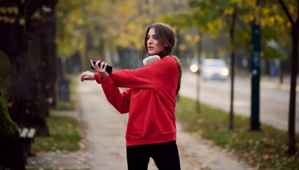 Athletic young woman taking a breath and relaxing after jogging and stretching. Woman Training and Workout Exercises On Street. Slim and fit girl stretching after active fitness training.