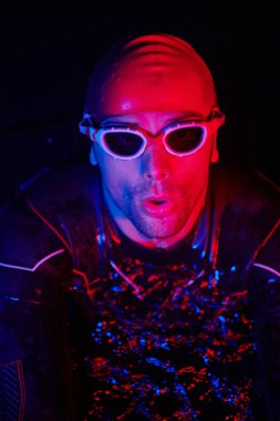 Gerçek bir triatlet yüzücüsüdür. Gölde, neon renkli ışıklarda sıkı bir antrenman sırasında mola verir.