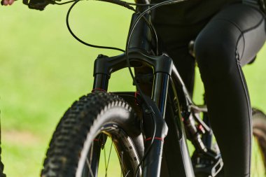 Bir spor bisikleti parkta yarışır, bileşenleri odaklanmış hareket döner tekerlekler, çevik pedallar ve şık gidonlar, arka planda dinamik bir atletizm ve hız gösterisi yaratır.