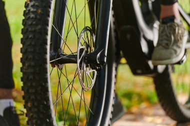 Bir spor bisikleti parkta yarışır, bileşenleri odaklanmış hareket döner tekerlekler, çevik pedallar ve şık gidonlar, arka planda dinamik bir atletizm ve hız gösterisi yaratır.
