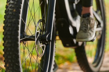 Bir spor bisikleti parkta yarışır, bileşenleri odaklanmış hareket döner tekerlekler, çevik pedallar ve şık gidonlar, arka planda dinamik bir atletizm ve hız gösterisi yaratır.