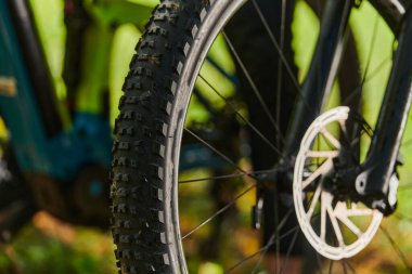 Bir spor bisikleti parkta yarışır, bileşenleri odaklanmış hareket döner tekerlekler, çevik pedallar ve şık gidonlar, arka planda dinamik bir atletizm ve hız gösterisi yaratır.