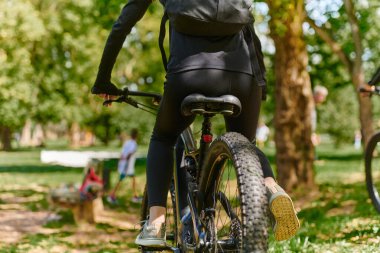 Bir spor bisikleti parkta yarışır, bileşenleri odaklanmış hareket döner tekerlekler, çevik pedallar ve şık gidonlar, arka planda dinamik bir atletizm ve hız gösterisi yaratır.