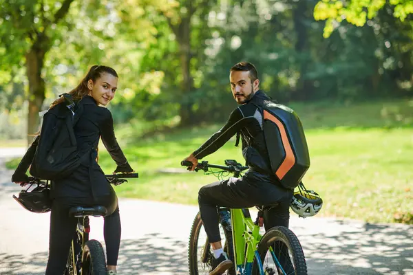 一对穿着职业自行车赛服的幸福的夫妇 在公园里骑着浪漫的自行车 周围环绕着现代的自然景观 散发着爱情和幸福的光芒 — 图库照片