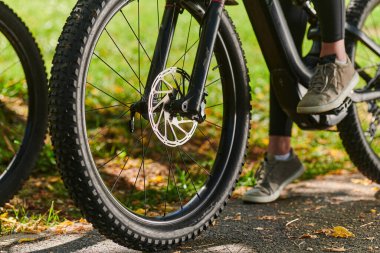 Bir spor bisikleti parkta yarışır, bileşenleri odaklanmış hareket döner tekerlekler, çevik pedallar ve şık gidonlar, arka planda dinamik bir atletizm ve hız gösterisi yaratır.