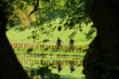 Profesyonel bisiklet kıyafetleriyle süslenmiş mutlu bir çift, parkın içinde romantik bir bisiklet sürmekten hoşlanıyor, modern doğal cazibelerle çevrili, sevgi ve mutluluk saçıyor.. 