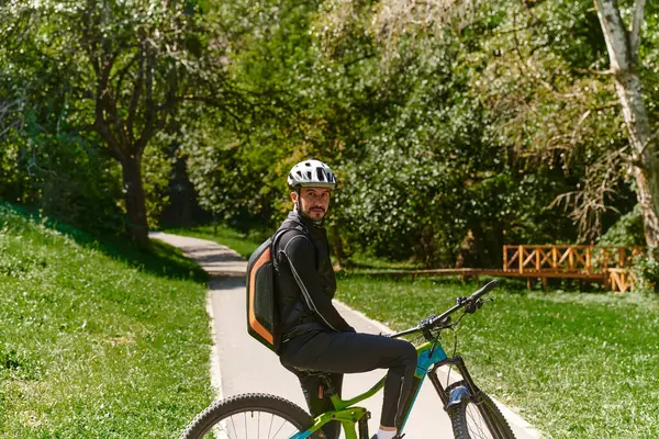 In the radiant glow of a sunny day, a fitness enthusiast, donned in professional gear, pedals through the park on his bicycle, embodying strength and vitality in a dynamic outdoor workout.