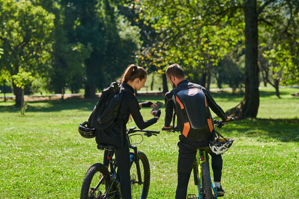 Блаженная пара, украшенная профессиональным велосипедным снаряжением, наслаждается романтической поездкой на велосипеде через парк, окруженный современными природными достопримечательностями, излучающими любовь и счастье. 