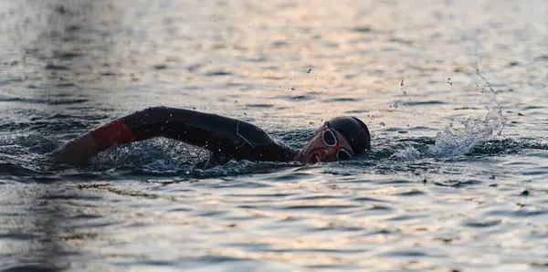 A professional triathlete trains with unwavering dedication for an upcoming competition at a lake, emanating a sense of athleticism and profound commitment to excellence