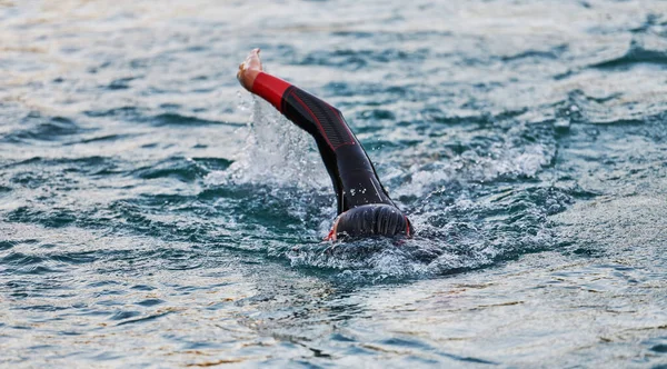 A professional triathlete trains with unwavering dedication for an upcoming competition at a lake, emanating a sense of athleticism and profound commitment to excellence