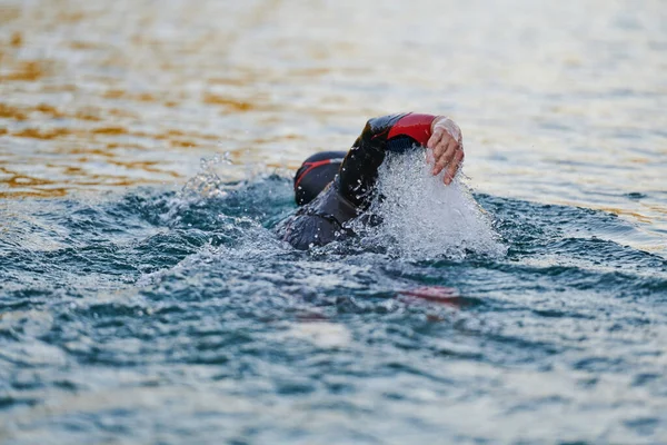 参加三项全能运动的运动员穿着湿衣在日出时在湖上游泳 高质量的照片 — 图库照片