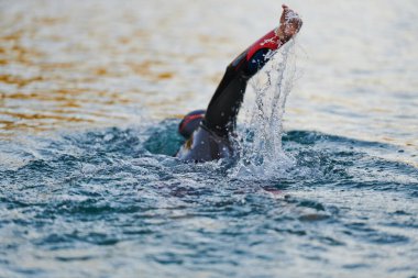 Güneşin doğuşunda gölde yüzen triatlon sporcusu. Dalgıç kıyafeti giymiş. Yüksek kalite fotoğraf