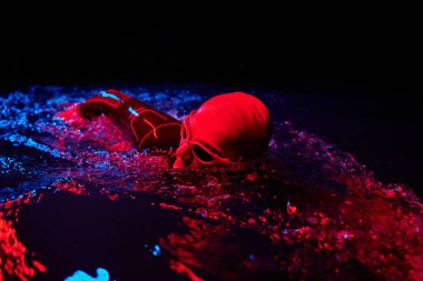 Gerçek bir triatlet yüzücüsüdür. Gölde, neon renkli ışıklarda sıkı bir antrenman sırasında mola verir.