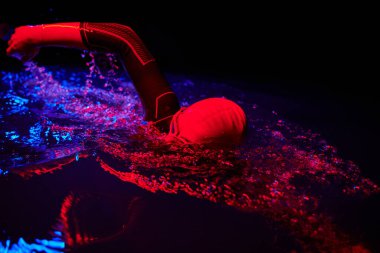 Gerçek bir triatlet yüzücüsüdür. Gölde, neon renkli ışıklarda sıkı bir antrenman sırasında mola verir.