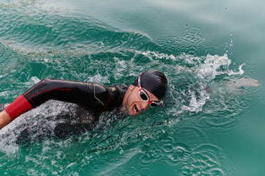 A professional triathlete trains with unwavering dedication for an upcoming competition at a lake, emanating a sense of athleticism and profound commitment to excellence clipart