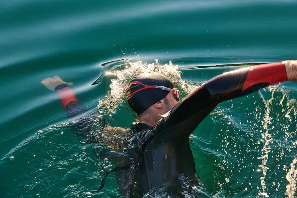 参加三项全能运动的运动员穿着湿衣在日出时在湖上游泳 高质量的照片 — 图库照片