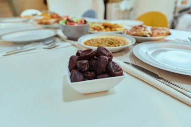 Resimli bir sıra hurma ve çeşitli, nefis yemekler masayı süslüyor, kutsal Ramazan ayı boyunca iftar yemeği için ihtişamlı bir ziyafet hazırlıyor, zengin bir duvar halısını somutlaştırıyor