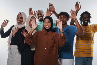 Coşkulu ve çeşitli bir grup, Afrika kökenli Amerikalı bir adam ve tesettürlü kızlar, coşkuyla el sallıyor ve kutluyorlar, öğrenci yaşamının canlılığını somutlaştırıyorlar, beyaz bir arka plana karşı,