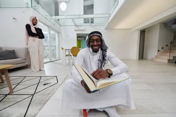 在神圣的斋月里 一位致力于阅读 古兰经 的非洲裔美国穆斯林男子被三个头戴头巾的女人包围着 她们正在为她们准备和供应花蜜食物 — 图库照片