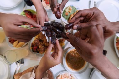 Dokunaklı bir yakın plan çekimde, Müslüman bir ailenin farklı elleri, kutsal Ramazan ayı boyunca orucun kırılışını sembolize ederek, kültürel birliğin bir anını yakalıyor.