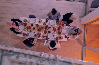 Müslüman bir ailenin üst görüşü neşeyle bir masanın etrafında toplanıyor, ortak iftarı hevesle bekliyor, ortak bir yemek hazırlıyor ve kolektif bir beklenti içinde birleşiyor.