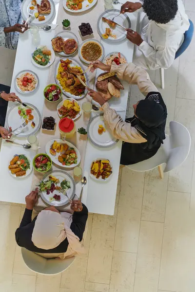 Top view of traditional and diverse Muslim family comes together to share a delicious iftar meal during the sacred month of Ramadan, embodying the essence of familial joy, cultural richness, and