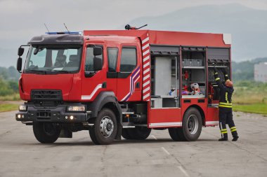 İtfaiyeci titizlikle modern bir itfaiye aracını tehlikeli durumlara müdahale ve boşaltma görevi için hazırlıyor. Yangına karşı güvenlik ve hazır olma azmini gösteriyor.