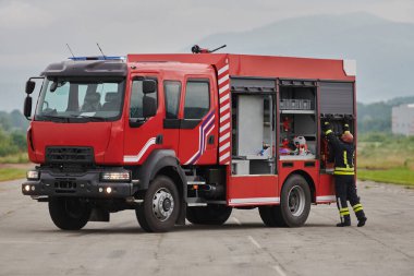 İtfaiyeci titizlikle modern bir itfaiye aracını tehlikeli durumlara müdahale ve boşaltma görevi için hazırlıyor. Yangına karşı güvenlik ve hazır olma azmini gösteriyor.