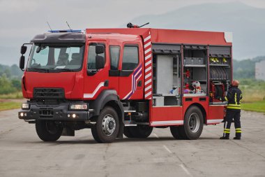 İtfaiyeci titizlikle modern bir itfaiye aracını tehlikeli durumlara müdahale ve boşaltma görevi için hazırlıyor. Yangına karşı güvenlik ve hazır olma azmini gösteriyor.