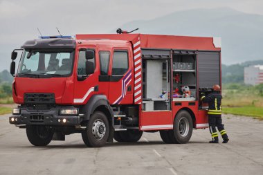 İtfaiyeci titizlikle modern bir itfaiye aracını tehlikeli durumlara müdahale ve boşaltma görevi için hazırlıyor. Yangına karşı güvenlik ve hazır olma azmini gösteriyor.