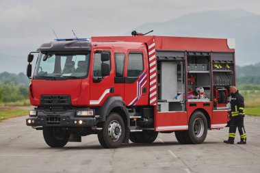 İtfaiyeci titizlikle modern bir itfaiye aracını tehlikeli durumlara müdahale ve boşaltma görevi için hazırlıyor. Yangına karşı güvenlik ve hazır olma azmini gösteriyor.