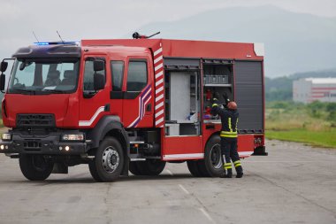 İtfaiyeci titizlikle modern bir itfaiye aracını tehlikeli durumlara müdahale ve boşaltma görevi için hazırlıyor. Yangına karşı güvenlik ve hazır olma azmini gösteriyor.