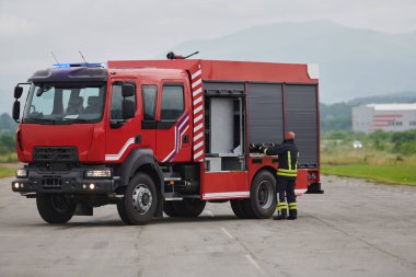 İtfaiyeci titizlikle modern bir itfaiye aracını tehlikeli durumlara müdahale ve boşaltma görevi için hazırlıyor. Yangına karşı güvenlik ve hazır olma azmini gösteriyor.