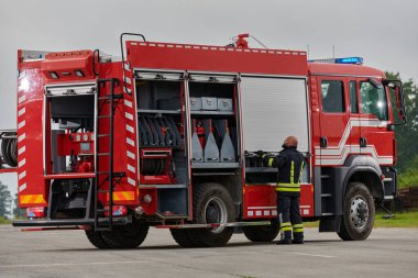 İtfaiyeci titizlikle modern bir itfaiye aracını tehlikeli durumlara müdahale ve boşaltma görevi için hazırlıyor. Yangına karşı güvenlik ve hazır olma azmini gösteriyor.