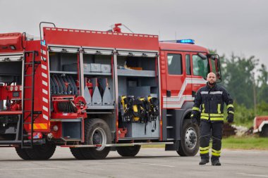 Sembolik olarak cesur bir itfaiyeci sarsılmaz bir cesaretle, azim ve liderliği simgeleyen bir adımla ilerlerken, arkasında itfaiye aracı itfaiye eylemleri için hazır bekliyor.