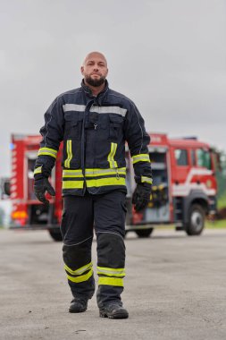 Sembolik olarak cesur bir itfaiyeci sarsılmaz bir cesaretle, azim ve liderliği simgeleyen bir adımla ilerlerken, arkasında itfaiye aracı itfaiye eylemleri için hazır bekliyor.