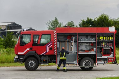 İtfaiyeci titizlikle modern bir itfaiye aracını tehlikeli durumlara müdahale ve boşaltma görevi için hazırlıyor. Yangına karşı güvenlik ve hazır olma azmini gösteriyor.