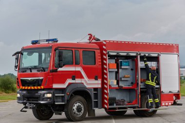 İtfaiyeci titizlikle modern bir itfaiye aracını tehlikeli durumlara müdahale ve boşaltma görevi için hazırlıyor. Yangına karşı güvenlik ve hazır olma azmini gösteriyor.