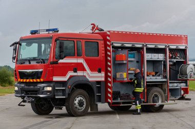 İtfaiyeci titizlikle modern bir itfaiye aracını tehlikeli durumlara müdahale ve boşaltma görevi için hazırlıyor. Yangına karşı güvenlik ve hazır olma azmini gösteriyor.